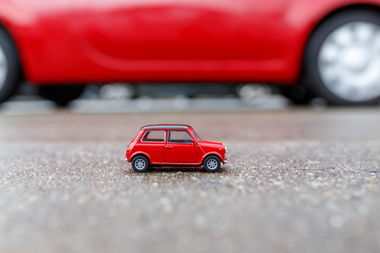 Een klein, rood modelautootje op het wegdek